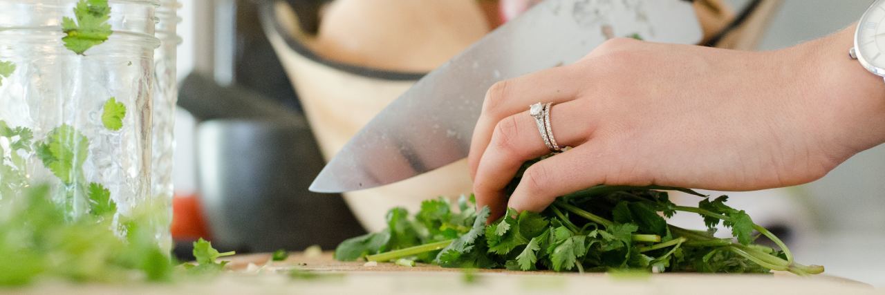 woman chopping herbs on a cutting board