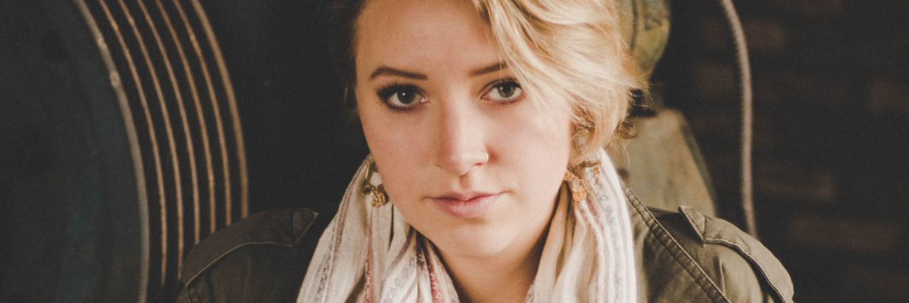 Should I Apologize for Self-Care With Bipolar Disorder? photo of young woman wearing scarf and green jacket looking serious into camera