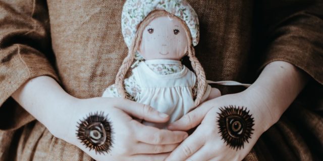 The Trauma Disorder You May Not Have Heard About photo of young girl with hamsas on hands holding doll to her dress