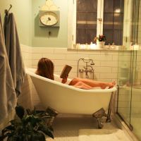 photo of woman in bath, reading a book, taken from afar