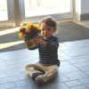Benji, a young boy holding a pot of colorful flowers.