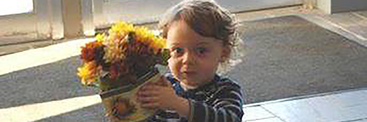 Benji, a young boy holding a pot of colorful flowers.