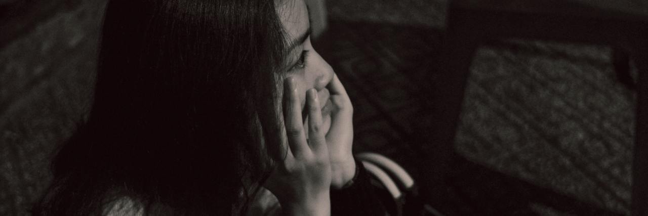 black and white photo of asian woman looking sad with chin on hands
