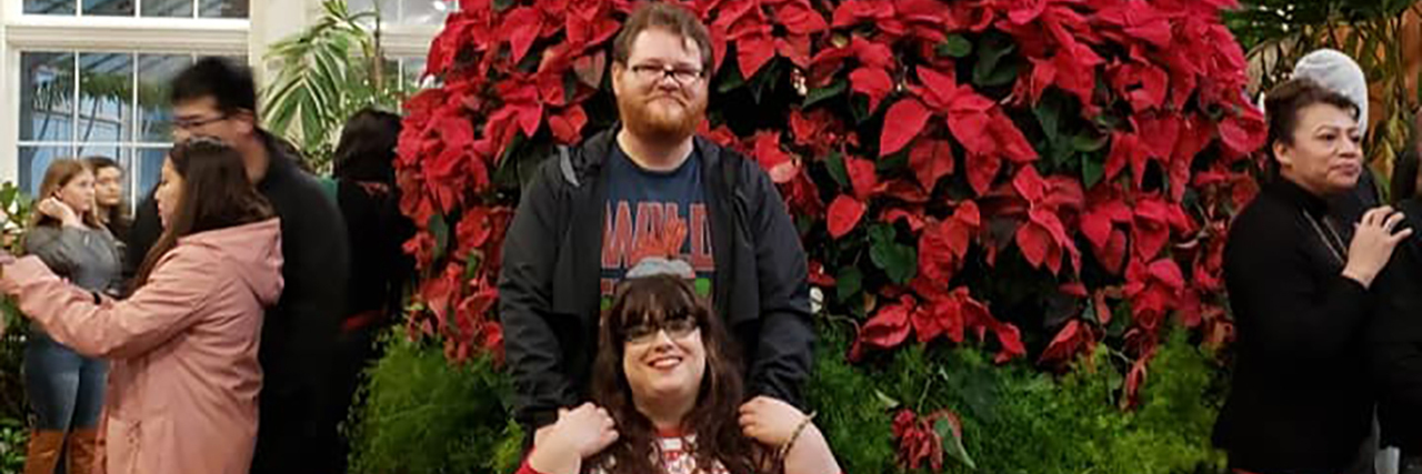 Responding to Dr. Phil's Ignorance About Interabled Relationships Jane with her boyfriend in front of a large poinsettia Christmas tree.
