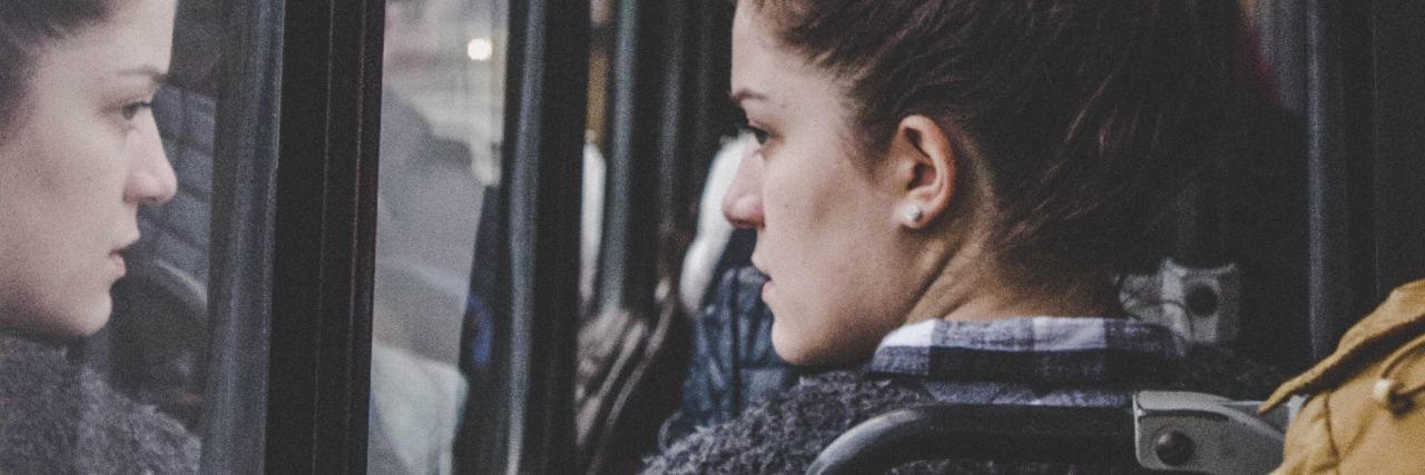 photo of woman sitting on bus looking mournfully out of window