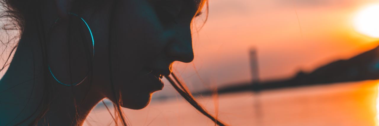 How a Lyme Disease Diagnosis Saved a Suicidal Woman's Life photo of woman silhouetted by sunset standing in front of ocean
