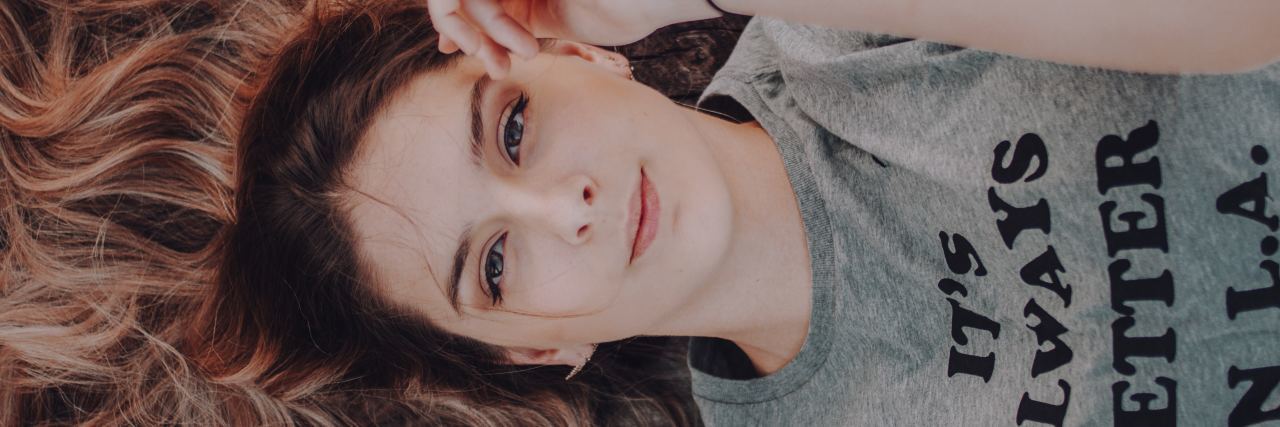 Important Things to Know About Mental Health and Feeling Better photo of woman lying down looking up into camera with slight smile