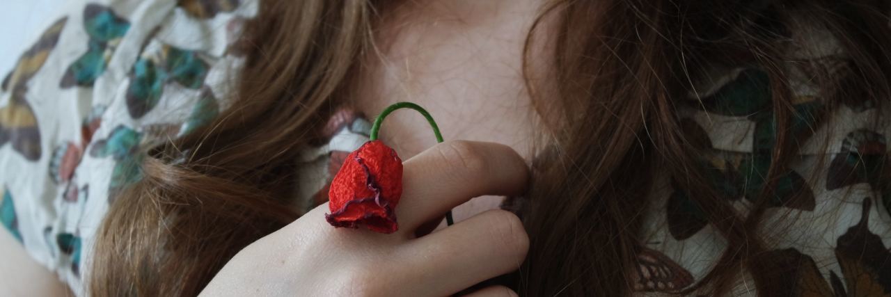 What Would Have Helped My Anxiety After a Breakup close up photo of woman holding small wilted rose close to chest