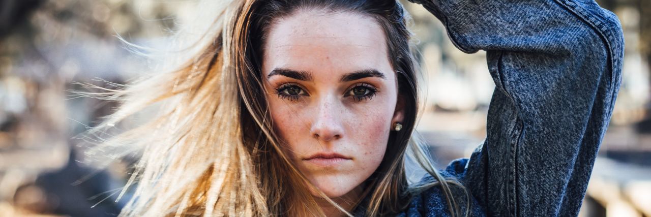What Can We Do to Help Young People After a Second Parkland Survivor Dies by Suicide photo of young woman looking into camera with serious expression and hand in hair