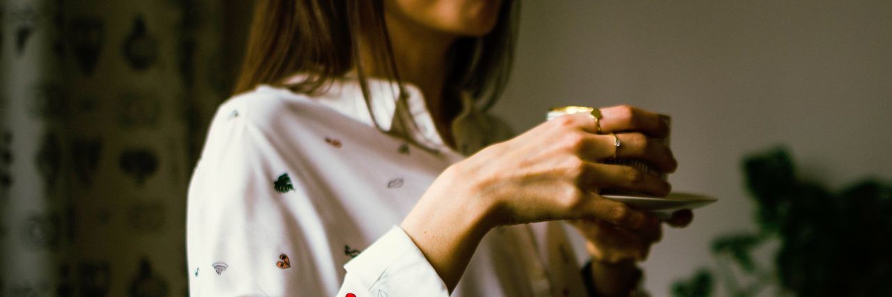 close up photo of woman drinking coffee wearing baggy white top