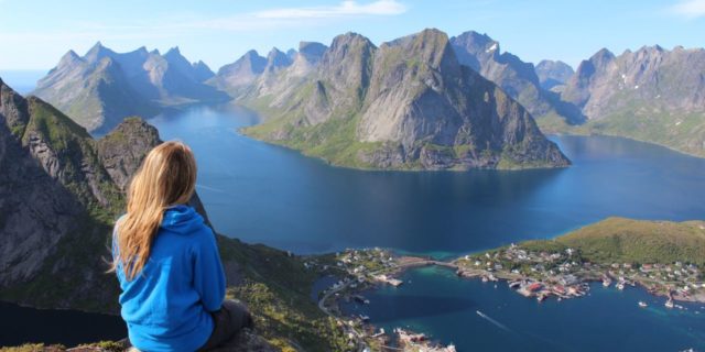 What to Know About Backpacking With Bipolar Disorder photo of young woman backpacking or traveling on top of mountain looking at mountains and lakes far below
