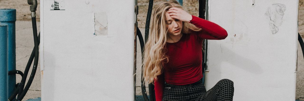 Are People With Mental Illness Attention Seekers? photo of young blonde woman sitting by pumps at gas station looking upset