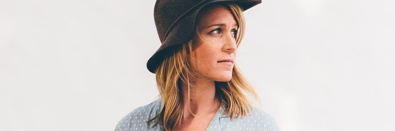 The Problem With the Standard Pain Scale for Chronic Pain photo of blonde woman looking away from camera and wearing dark hat