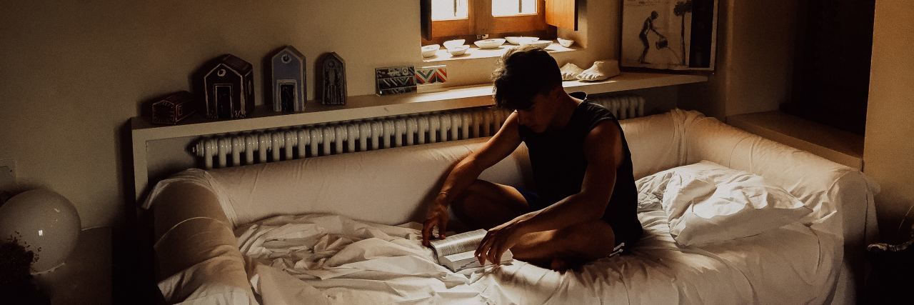 Why Anxiety Makes Me Too Tired to Get out of Bed photo of young middle eastern man sitting on bed looking exhausted