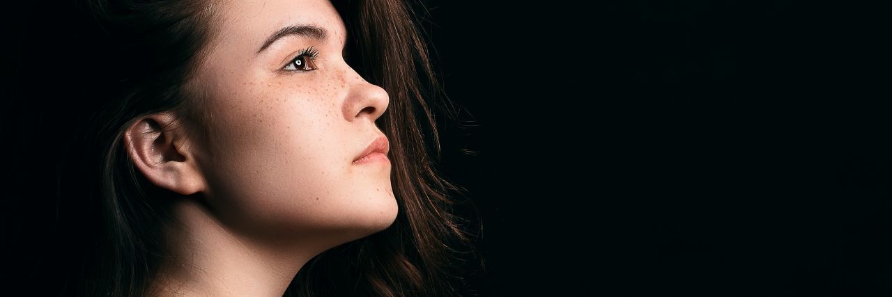 What You Need to Remember This Sexual Assault Awareness Month photo of young woman cast in light against black background with head raised high