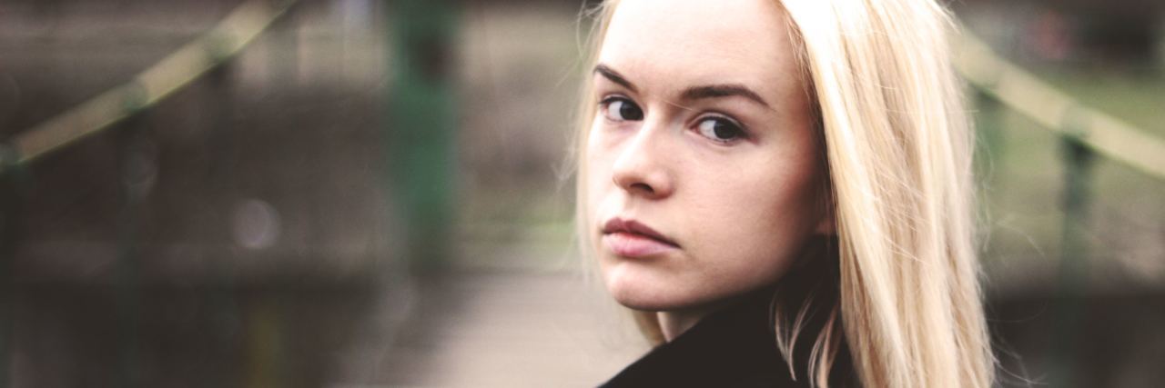 What to Know If You Have a 'Narcissistic' Parent photo of blonde teen standing on bridge looking over her shoulder