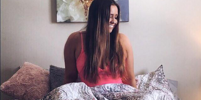 photo of contributor Megan Rowe sitting on bed smiling