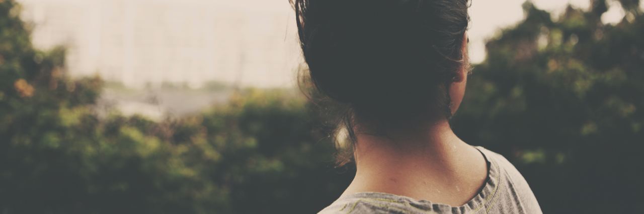 How to Cope With 'Diabetes Burnout' woman in gray t-shirt with her hair in a bun looking out over trees