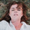 A woman wearing a white shirt laying in the grass
