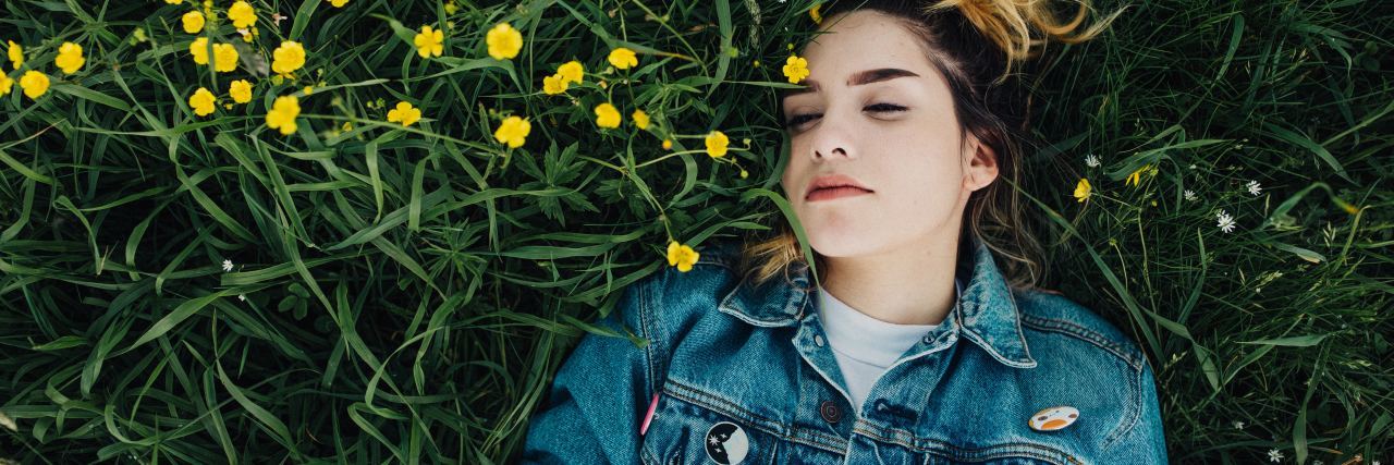 photo of young woman lying in flowers with eyes closed