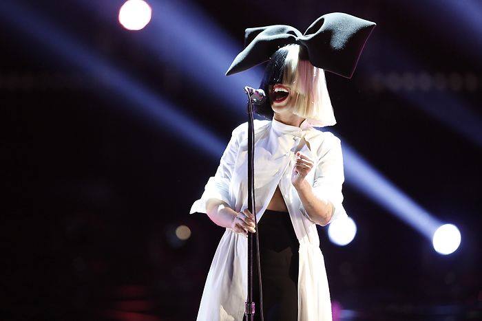 sia with bow in hair singing on stage