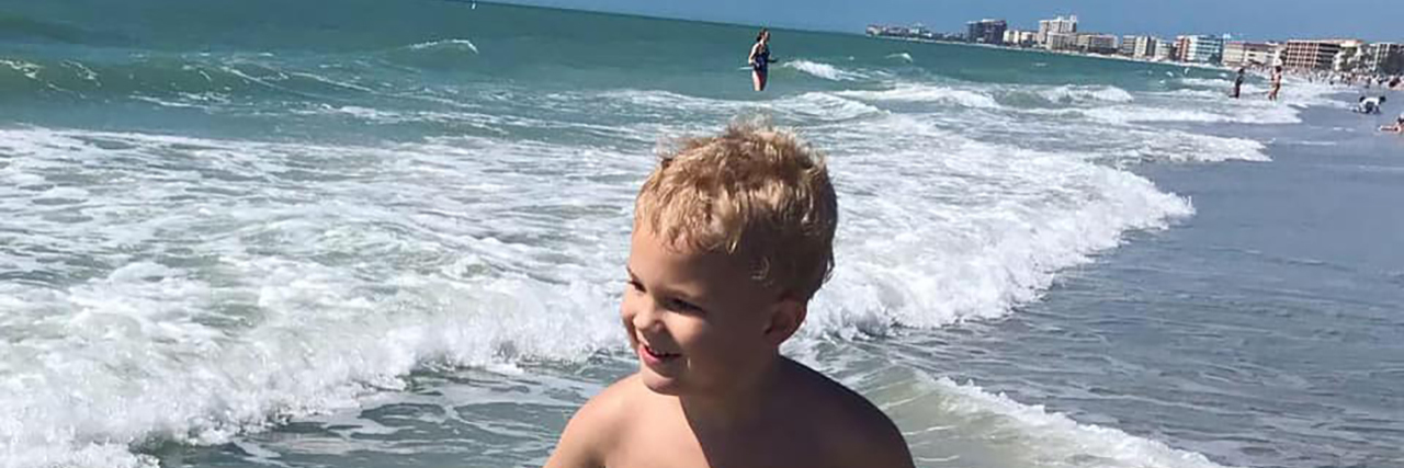 Autism Is Not a Tragedy Boy playing in the ocean.