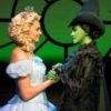 photo of characters from wicked facing each other and holding hands