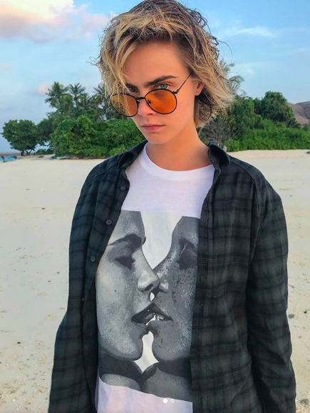 Cara Delevingne standing on a beach.