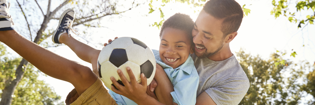 When I Realized I Was 'Checking Out' as a Dad of a Child With Autism Father helping son kick a soccer ball.