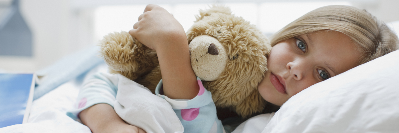 Please Don’t Take Your Kids With Chickenpox to Public Places a sick girl laying in bed hugging her teddy bear