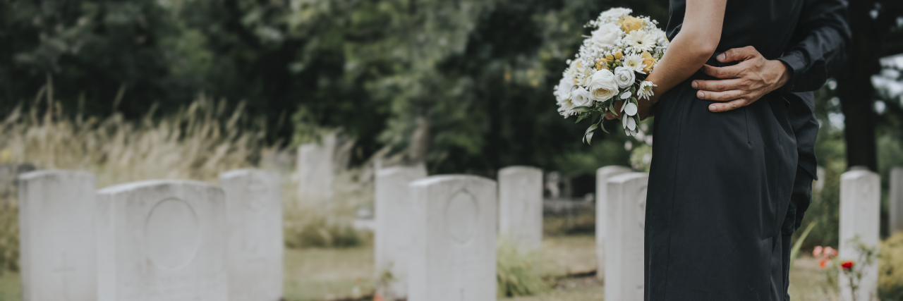 a couple is standing at a gravestone