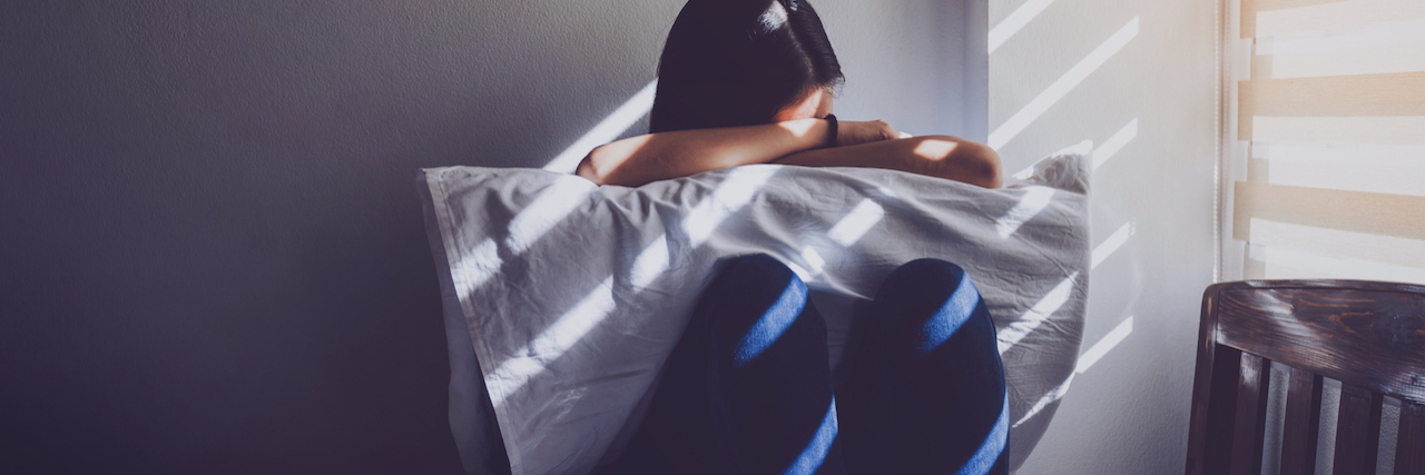 Redefining 'Burden' When You Live With a Chronic Illness A woman holding her pillow