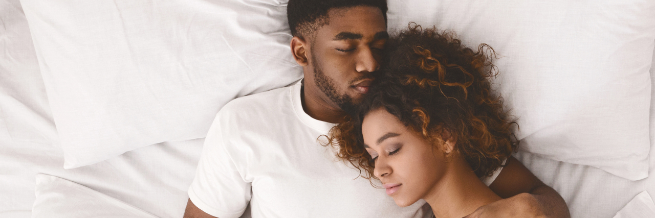 Young black couple sleeping together in bed