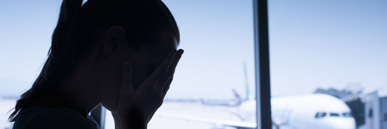 a woman stressed sitting next to window at an airport