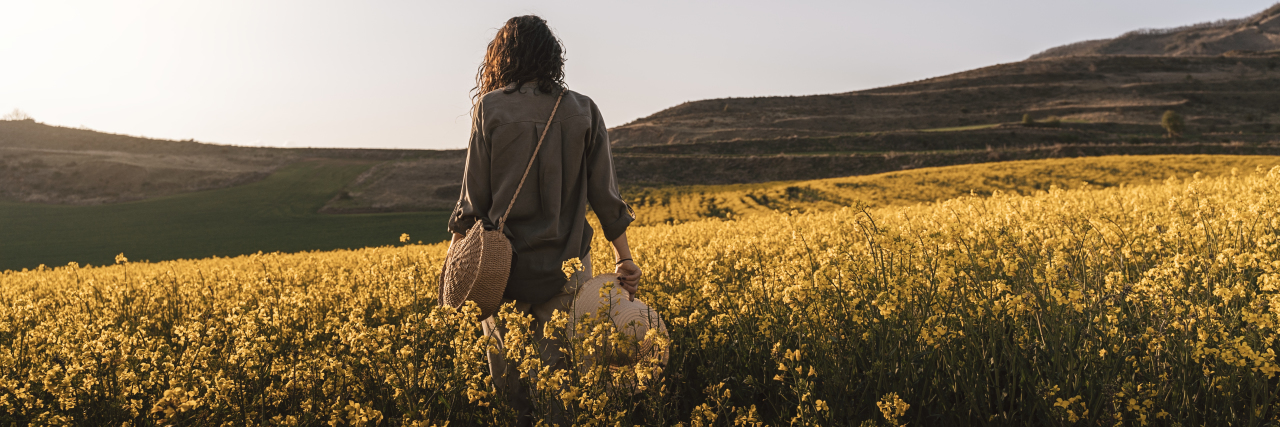 a woman alone walking in a field of flowers