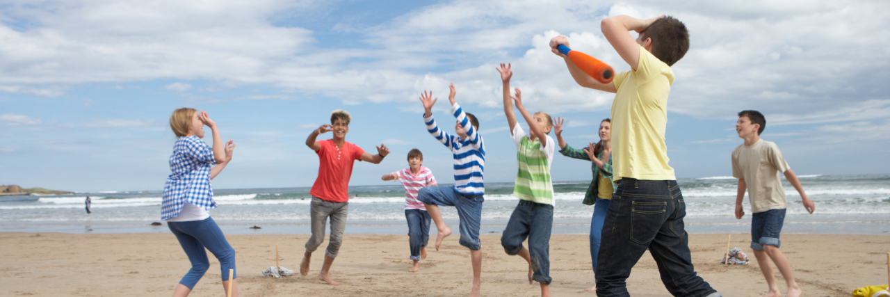 Helping Neurotypical and Autistic Children Play Together Children playing baseball on beach.