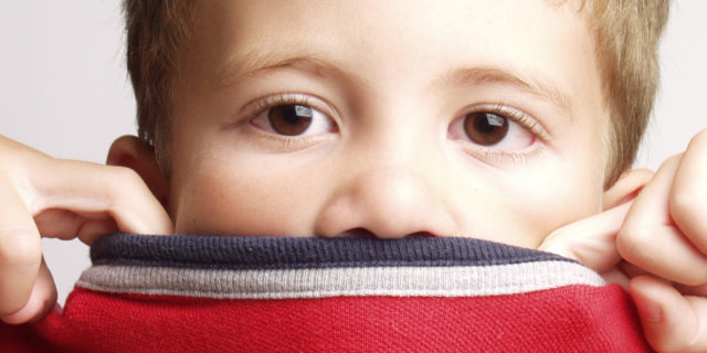 Child covering mouth with red sweater