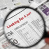 Magnifying glass over Jobs section of newspaper classifieds.