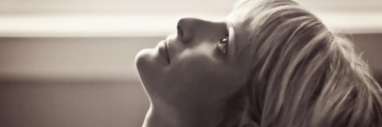 I'm a Former 'Juvenile Delinquent' Because of Childhood Trauma black and white sepia toned photo of woman lying head back against back of sofa looking up with sad expression