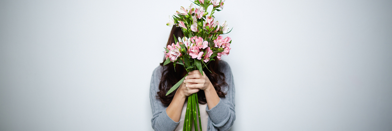 Why I'm Celebrating 'Toxic Parent Day' After Mother's Day A woman hiding behind a bouquet of flowers