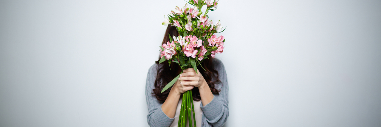 A woman hiding behind a bouquet of flowers