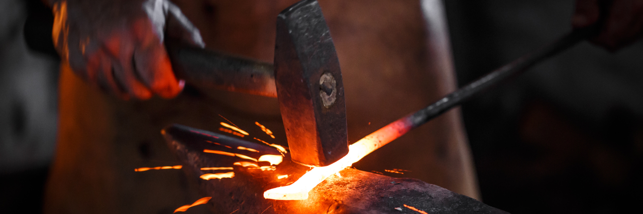 Blacksmith manually forging molten metal.