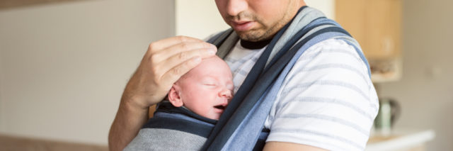 Father holding baby in sling.