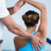 Physiotherapist giving shoulder therapy to a woman.