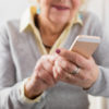 Senior woman holding smartphone in hands and exploring new technology