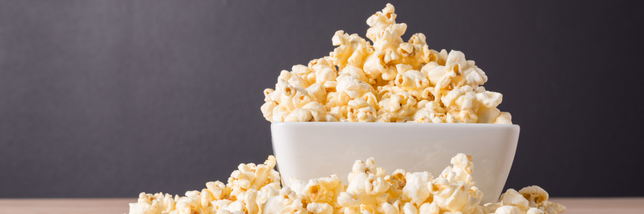 Popcorn in white bowl on wood background