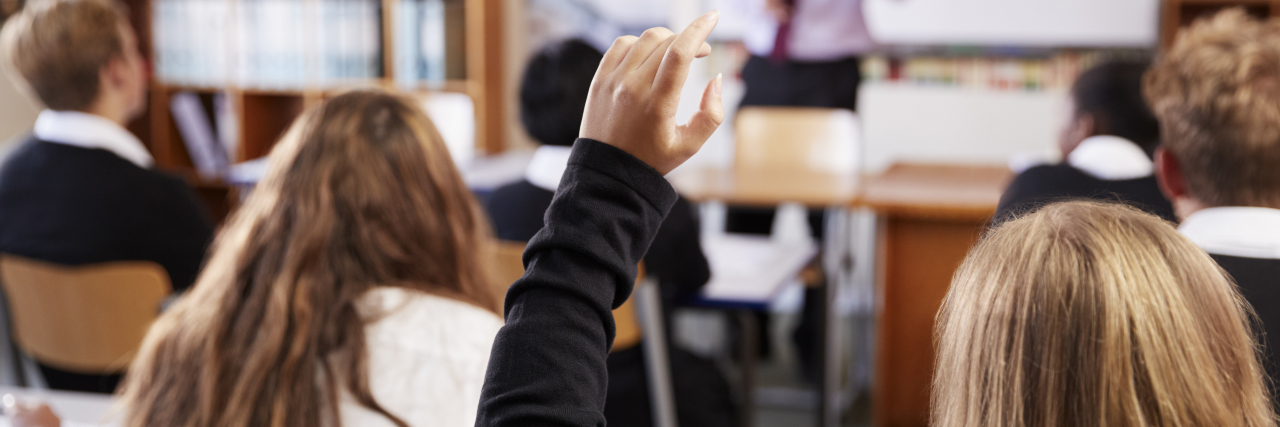 When Teachers Dismiss Students With Chronic Illness Female Student Raising Hand To Ask Question In Classroom