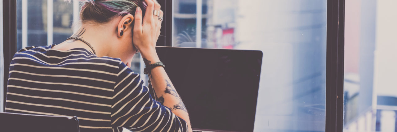 Why Making Your Cancer Treatment Choices Can Feel Lonely woman sitting in front of laptop with her head in her hands