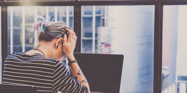 Why Making Your Cancer Treatment Choices Can Feel Lonely woman sitting in front of laptop with her head in her hands
