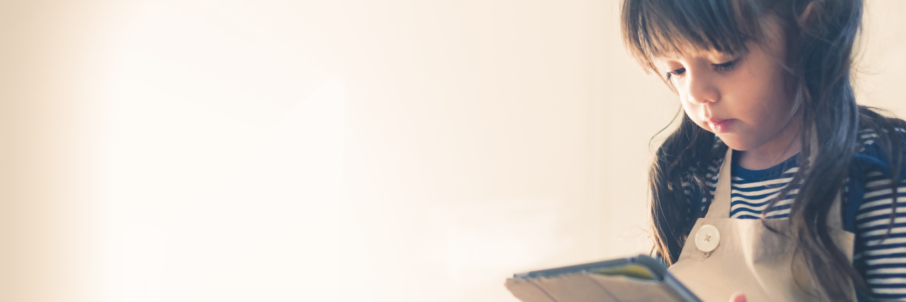 Why My Daughter With ADHD Needs to Take Breaks Little girl watching a video on her iPad.